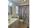 Well-lit bathroom featuring a vanity with a sink, toilet, and shower with patterned curtain at 432 Olivia Rd, Venice, FL 34293
