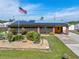 Charming one-story brick home with solar panels, an American flag, landscaped yard, and a welcoming entrance at 530 Lakemont Nw Ave, Port Charlotte, FL 33952