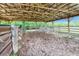 Covered wooden barn with a metal roof surrounded by greenery and secure fencing at 6171 Swiss Blvd, Punta Gorda, FL 33982