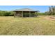 Exterior shot showing the barn's location within a grassy field surrounded by trees and clear blue skies at 6171 Swiss Blvd, Punta Gorda, FL 33982