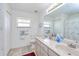Clean bathroom with double vanity, bright lighting, and a shower with a palm tree-themed curtain at 6171 Swiss Blvd, Punta Gorda, FL 33982