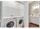 Bright laundry room featuring a washer, dryer, wire shelving, and adjacent bathroom with modern fixtures at 6251 Cassia St, Bradenton, FL 34203