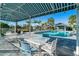 Relaxing pool area with shaded seating, palm trees, and a pristine pool, perfect for outdoor enjoyment at 6251 Cassia St, Bradenton, FL 34203