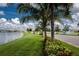 Scenic view of the community lake with a fountain, lush landscaping, and palm trees along the road at 7049 Waterford Pkwy, Punta Gorda, FL 33950