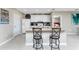 Bright kitchen with white cabinets, countertop seating, and a view to an adjoining room with a bed at 7049 Waterford Pkwy, Punta Gorda, FL 33950
