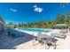 Resort-style community pool with ample seating, lush landscaping, and shade structures on a sunny day at 7049 Waterford Pkwy, Punta Gorda, FL 33950