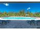 Inviting community pool with plenty of lounge chairs surrounded by mature trees under a bright blue sky at 7049 Waterford Pkwy, Punta Gorda, FL 33950