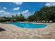 Beautiful community pool surrounded by palm trees and a brick paved deck on a sunny day at 7049 Waterford Pkwy, Punta Gorda, FL 33950