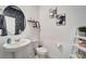 Stylish powder room features a pedestal sink, round mirror, decorative shelves, and modern art at 11637 Woodleaf Dr # 11637, Bradenton, FL 34211