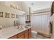 Well-lit bathroom with wood cabinets, a large mirror, and a shower with a patterned curtain at 1578 Scarlett Ave, North Port, FL 34289