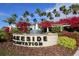 Lakeside Plantation's entrance features a beautiful water feature, lush bougainvillea, and majestic palm trees against a blue sky at 1578 Scarlett Ave, North Port, FL 34289