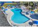 Aerial view of community pool with hot tub, sun umbrellas, lounge chairs and mature landscaping at 1578 Scarlett Ave, North Port, FL 34289