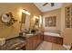 A double vanity bathroom with granite counters, decorative mirrors, and a soaking tub at 1620 Lancashire Dr, Venice, FL 34293