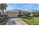 Charming single-story home with a tile roof, lush landscaping, and a paver driveway at 1620 Lancashire Dr, Venice, FL 34293