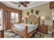 Elegant main bedroom with a wood frame bed, decorative ceiling fan, and palm tree pillows at 1620 Lancashire Dr, Venice, FL 34293