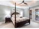 A spacious bedroom featuring a four-poster bed, tray ceiling with fan, and sliding glass doors to the outdoors at 17122 Barcrest Ln, Punta Gorda, FL 33955