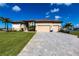 Charming home featuring a wide driveway, three-car garage, manicured lawn, and mature palm trees at 17122 Barcrest Ln, Punta Gorda, FL 33955