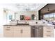 Kitchen island with white cabinets, stainless steel dishwasher, sink, and granite countertops in a bright, open space at 17122 Barcrest Ln, Punta Gorda, FL 33955