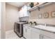 Functional laundry room featuring granite countertops, front load washer and dryer, and white cabinetry at 17122 Barcrest Ln, Punta Gorda, FL 33955