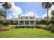 Front elevation of a clubhouse with a lawn, trimmed shrubs, tropical landscaping, and palm trees at 1771 Scarlett Ave, North Port, FL 34289