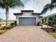 Charming home featuring a gray garage door, red tile roof, brick paved driveway, and well-maintained landscaping at 2478 Brassica Dr, North Port, FL 34289