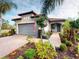 Inviting exterior showcasing lush landscaping, a brick walkway, a vibrant garden, and a charming teal front door at 2478 Brassica Dr, North Port, FL 34289