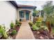 Inviting entrance with a brick path, teal door, and beautiful landscaping creating a warm welcome at 2478 Brassica Dr, North Port, FL 34289