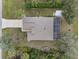 Aerial view of the home showcasing the roof, a long driveway, screened patio, and mature landscaping at 2621 San Maria Cir, North Port, FL 34286