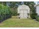 Charming backyard shed featuring barn doors, board and batten siding, and a manicured garden at 2621 San Maria Cir, North Port, FL 34286