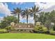 A beautiful stone community entrance sign surrounded by lush landscaping and swaying palm trees at 2639 Hobblebrush Dr, North Port, FL 34289