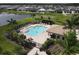 Aerial shot of a resort-style pool with sun loungers, a cabana, and lush landscaping at 2639 Hobblebrush Dr, North Port, FL 34289