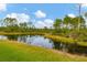 Scenic view of a tranquil pond surrounded by lush greenery and trees, creating a peaceful natural setting at 2639 Hobblebrush Dr, North Port, FL 34289