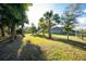 Fenced backyard showcasing palm trees, green spaces, and view of the home at 27385 Neaptide Dr, Punta Gorda, FL 33983