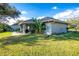 Spacious backyard with a screened lanai, lush banana trees, and a partial view of the home's exterior at 27385 Neaptide Dr, Punta Gorda, FL 33983