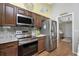 Kitchen features stainless steel appliances, wood cabinets and opens to living room at 27385 Neaptide Dr, Punta Gorda, FL 33983