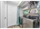 Well-organized laundry room featuring stainless steel washer/dryer, storage shelves, and bifold doors at 27385 Neaptide Dr, Punta Gorda, FL 33983