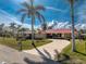 Inviting single-story home featuring a well-manicured front yard, a red metal roof, and mature palm trees at 35 Sabal Dr, Punta Gorda, FL 33950