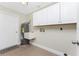 Laundry room with overhead cabinets, a utility sink, and neutral colored tile floors at 35 Sabal Dr, Punta Gorda, FL 33950