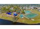 Aerial view of the community park featuring a playground, tennis court, basketball court, bocce ball, and lake access at 4383 Mckibben Dr, North Port, FL 34287