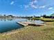 Scenic view of a community dock on a calm lake, surrounded by lush greenery and residential homes at 4383 Mckibben Dr, North Port, FL 34287