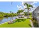 Waterfront backyard featuring artificial turf, tropical plants, and a boat lift at 5196 Early Ter, Port Charlotte, FL 33981