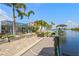 Waterfront home featuring a private dock, boat lift, and outdoor patio surrounded by lush landscaping and palm trees at 5196 Early Ter, Port Charlotte, FL 33981