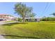 Well-manicured front yard featuring lush green lawn, mature trees, and charming single-story home at 5196 Early Ter, Port Charlotte, FL 33981