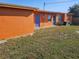 Backyard view shows the home's orange exterior and blue doors with well-maintained green grass at 520 Sharon Cir, Port Charlotte, FL 33952