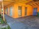 Spacious carport area showcasing the home's orange exterior and blue doors, providing ample covered parking at 520 Sharon Cir, Port Charlotte, FL 33952