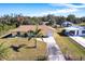 Aerial view of charming yellow single Gathering home with an expansive lawn and a long concrete driveway at 8029 Roy Dr, Punta Gorda, FL 33982