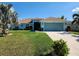 Charming single-story home with a well-manicured lawn, palm trees, and a two-car garage, showcasing curb appeal at 9175 Melody Cir, Port Charlotte, FL 33981