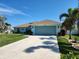 Single-story home featuring a two-car garage, lush lawn, and tropical landscaping, creating a desirable curb appeal at 9175 Melody Cir, Port Charlotte, FL 33981