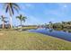 Spacious backyard with a waterfront view, mature palm trees, and a private dock, creating an outdoor oasis at 9428 Bandera Ln, Port Charlotte, FL 33981