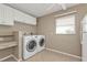 Functional laundry room featuring a washer, dryer, overhead cabinets, and a built-in desk at 9428 Bandera Ln, Port Charlotte, FL 33981